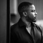 A dramatic black and white portrait of a thoughtful man looking to the side.